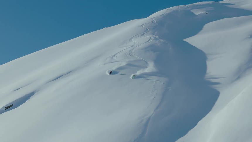 Aerial view of two people skiing down a snowy mountain