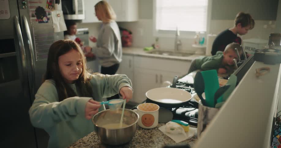 Mother in the kitchen with her four young children helping to cook