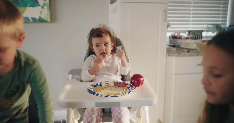 Little girl sitting eating next to other children