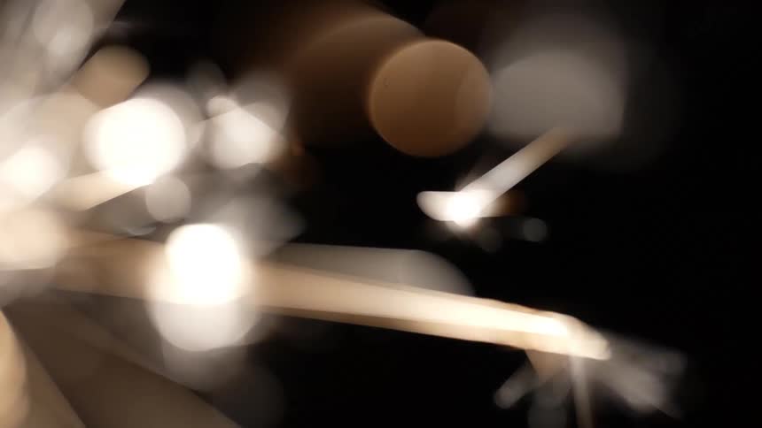 A lit sparkler emitting bright white sparks against a dark background