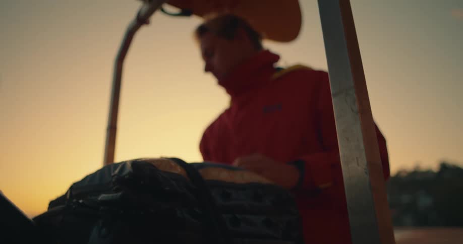 Man in jacket next to bag outdoors