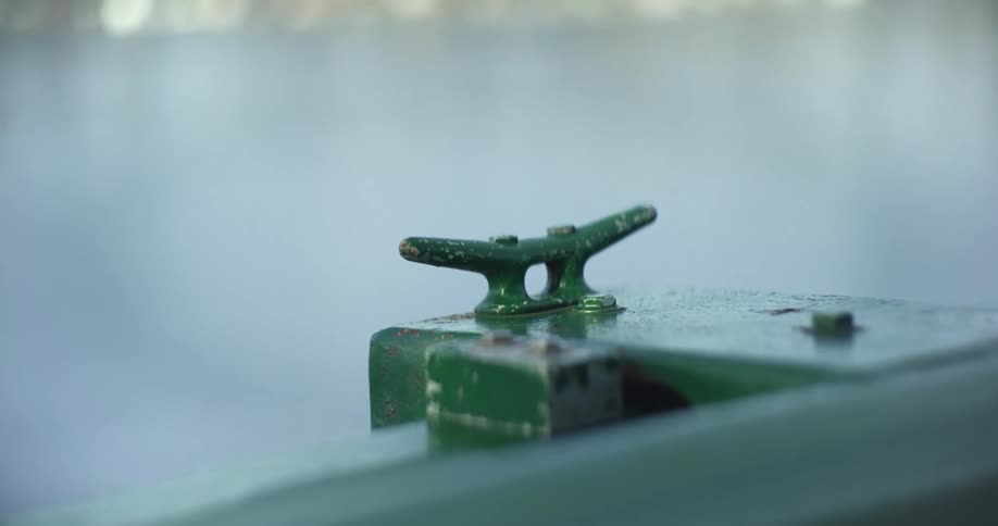 Closeup of a metallic green mooring on a boat with blurred water in the background