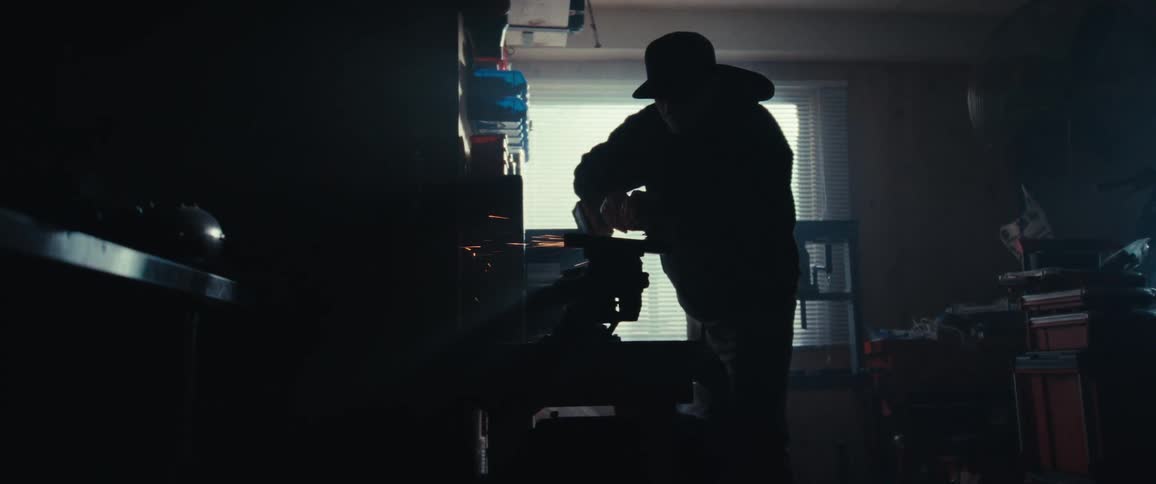 Silhouette of a man in a cap welding a motorcycle with sparks leaking