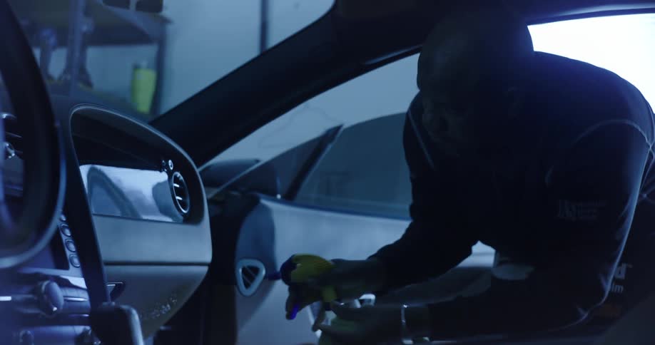 Man with a spray bottle spraying the inside of a vehicle