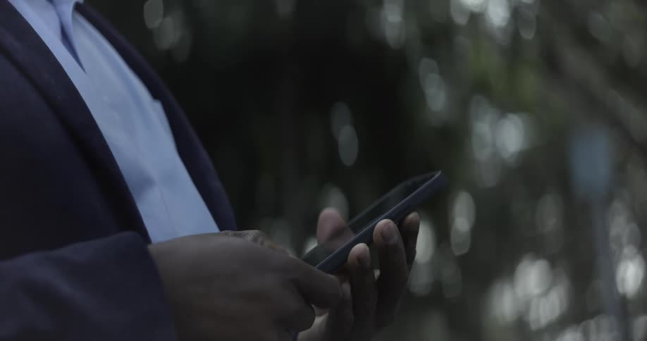 Pair of hands of a person in a suit interacting with a smartphone