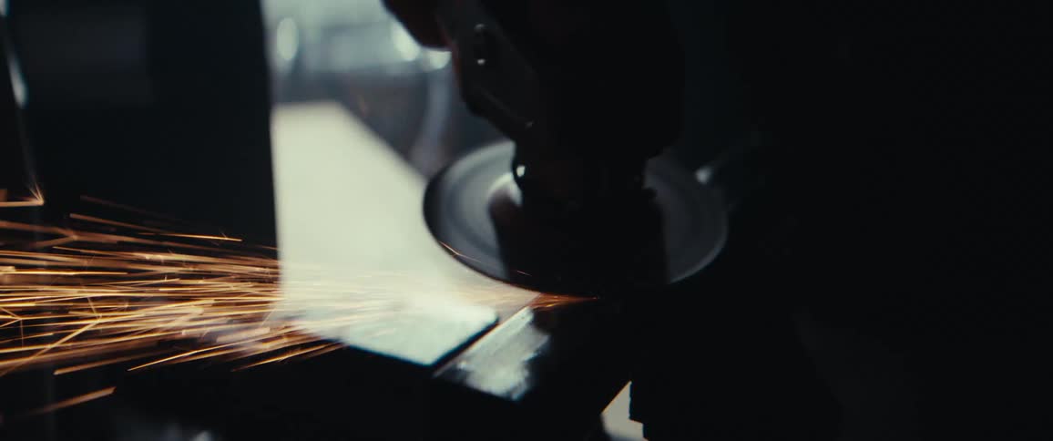 A worker is using an angle grinder on metal