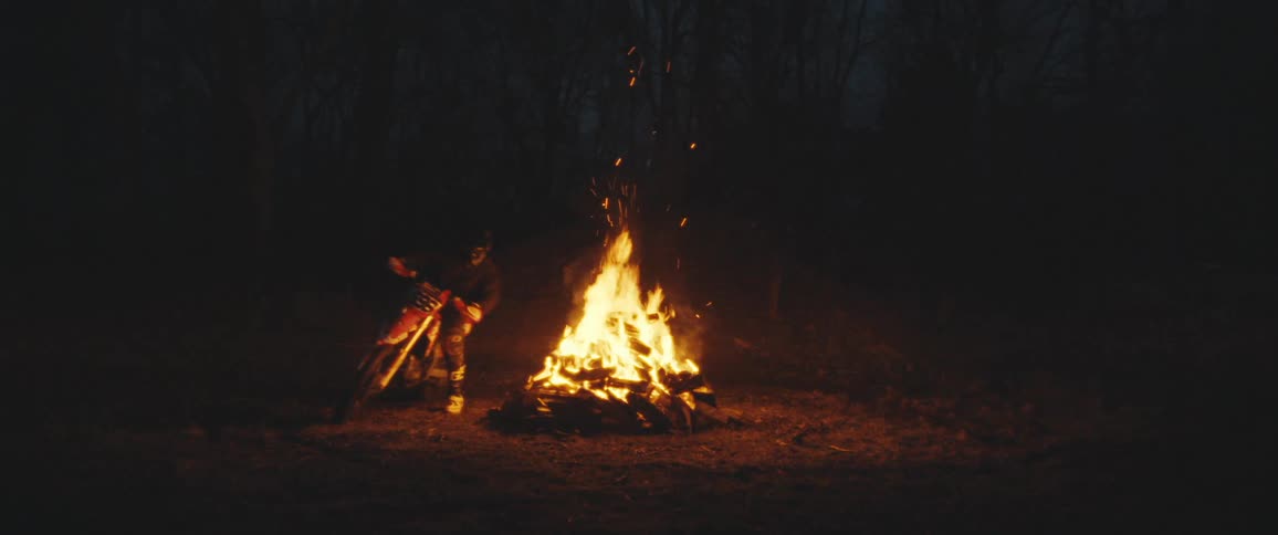 A man is driving around the bonfire at night