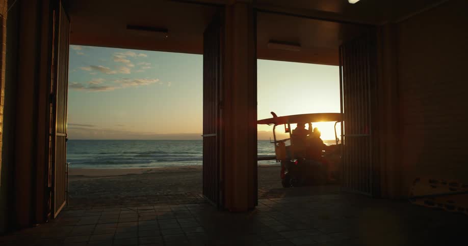 Two people riding a buggy on the sand with the sea in the background