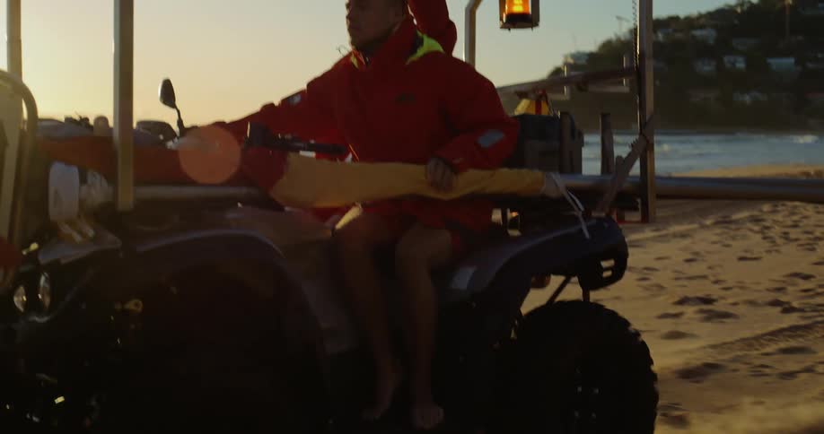 Two lifeguards riding a buggy on the beach sand