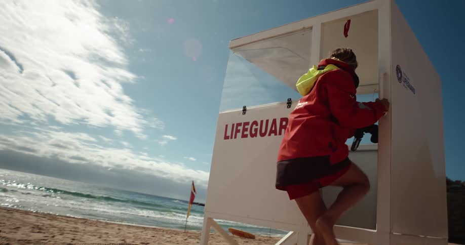 Lifeguard in red jacket entering observation cabin on a sunny beach