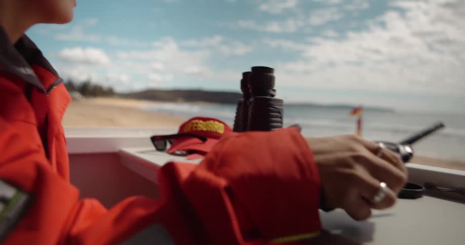 A lifeguard picks up a walkie talkie on the beach