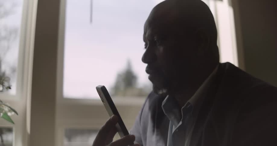 Man in a suit sitting in an armchair and interacting with a smartphone