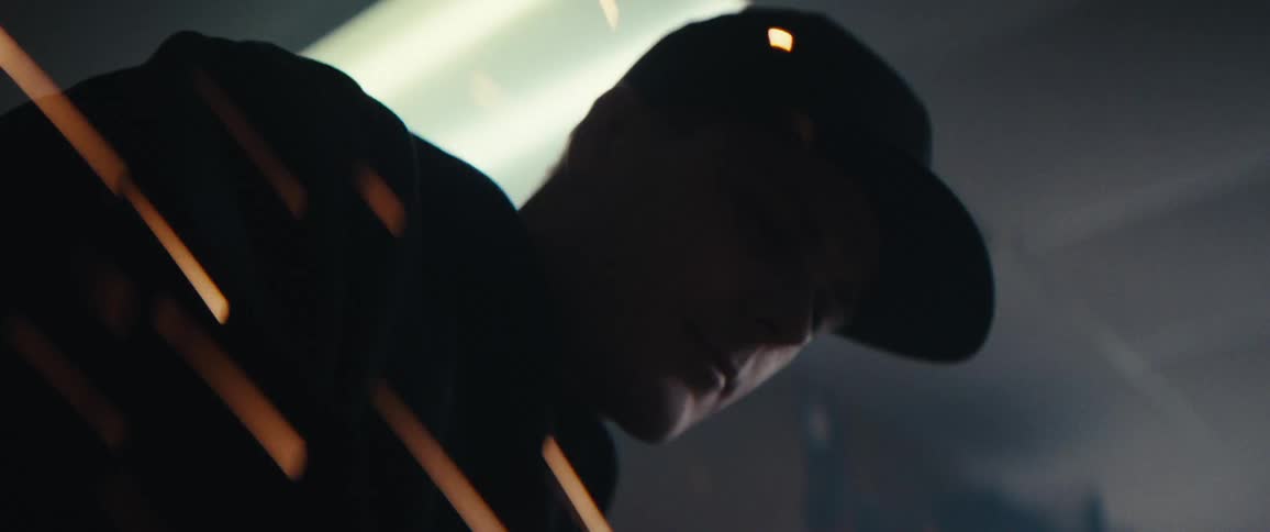 A person wearing a cap is partially visible through streaks of light or sparks