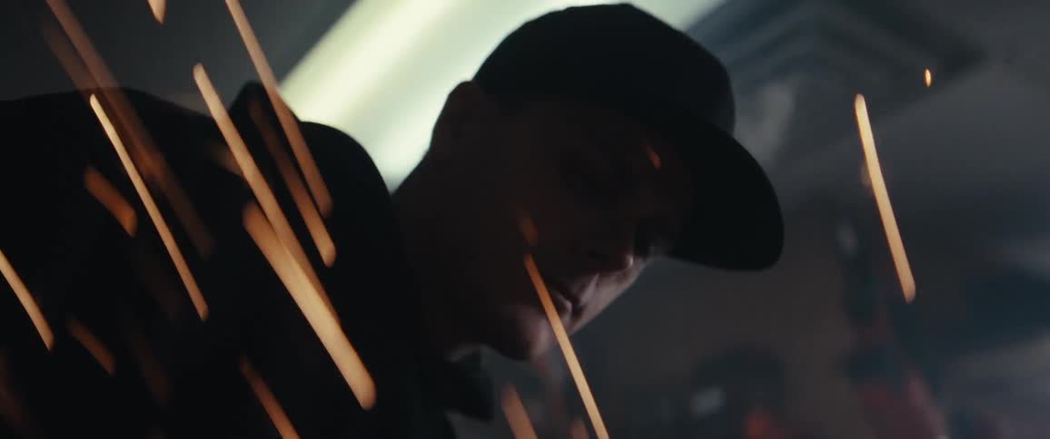 A person wearing a cap is partially visible through streaks of light or sparks