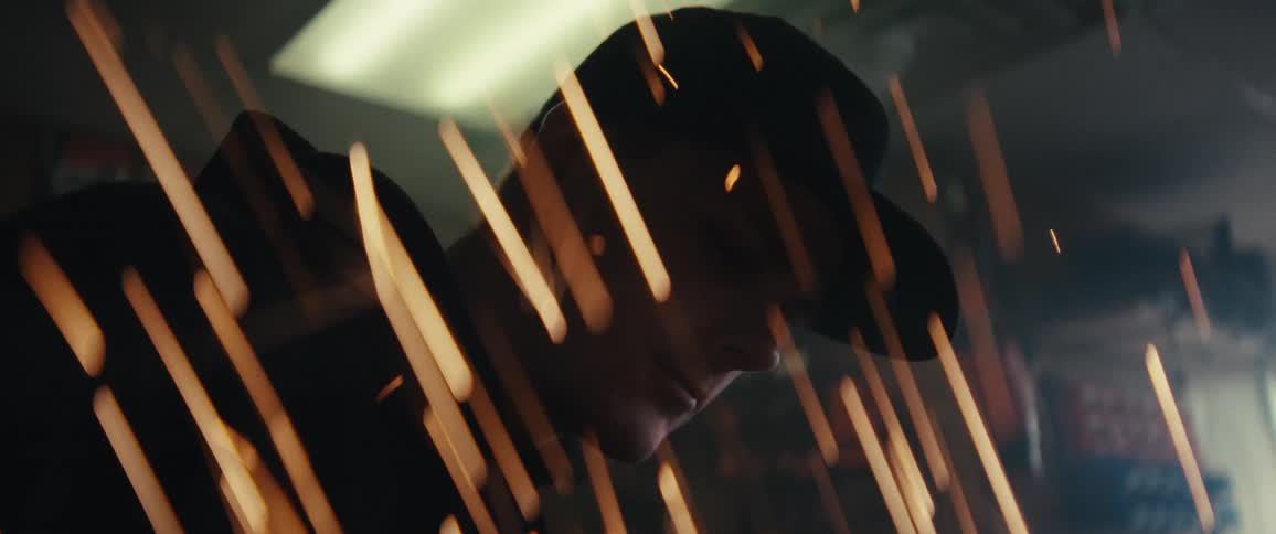 A person wearing a cap is partially visible through streaks of light or sparks