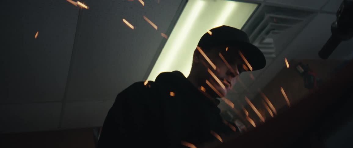 Portrait of a man in a cap working on a motorcycle and sparks flying