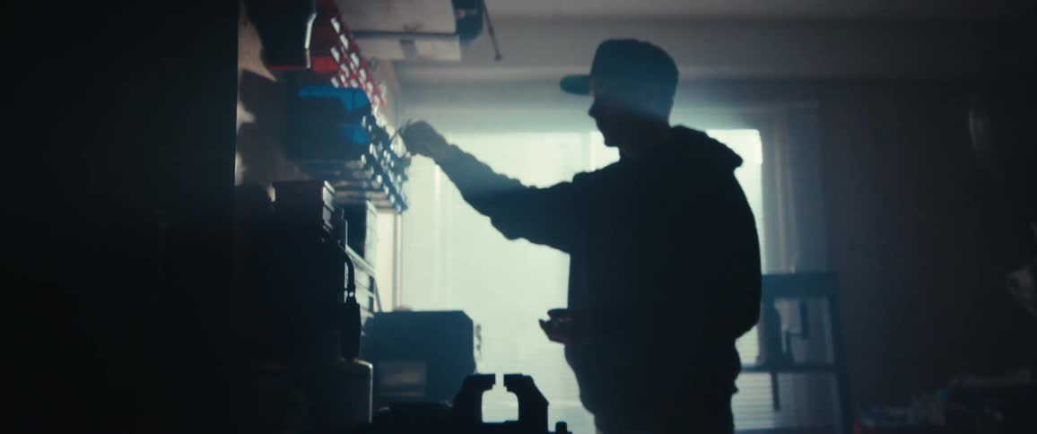 Man in cap picking up tools from boxes in a workshop