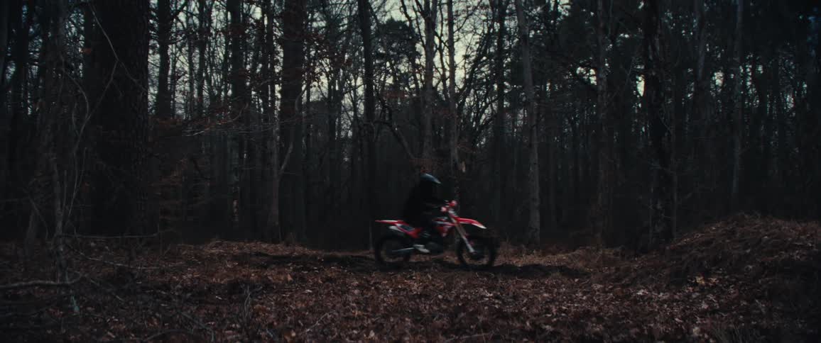 Person in helmet riding motocross in forest