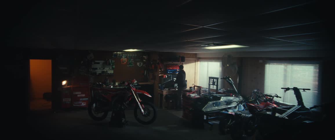 A man walks over to the dirt bike in the workshop