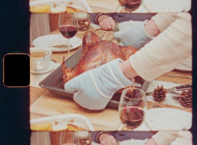 Hand with gloves placing a roast chicken in the middle of the wooden table