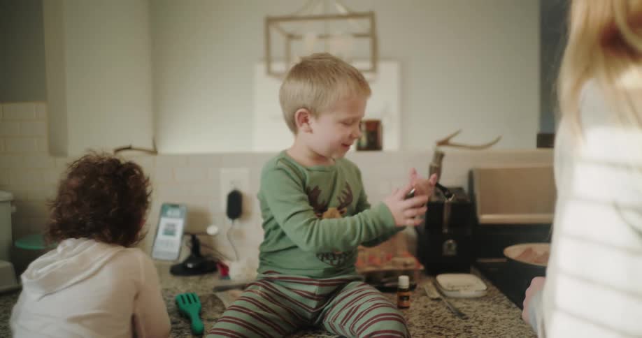 Children play on the kitchen counter while an adult cooks nearby