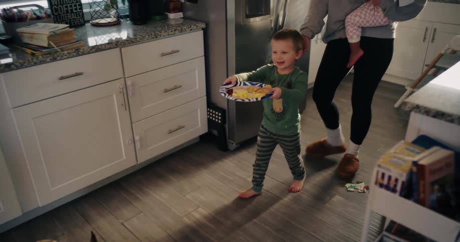A child walks through the kitchen with food