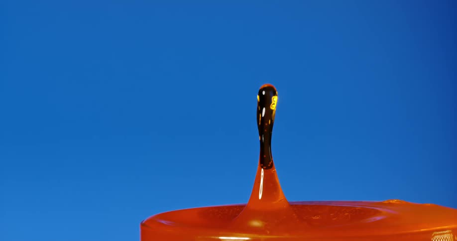 Droplet falls into a cup that is full to the rim creating a splash