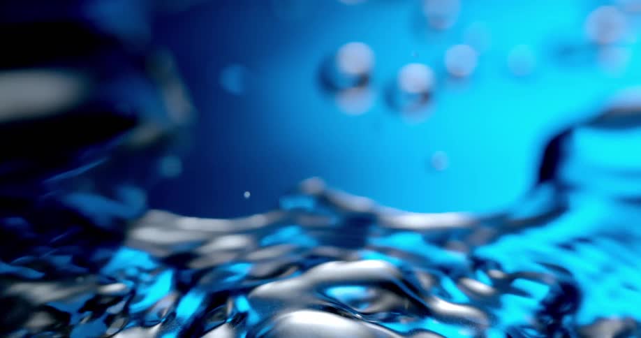 Water droplets splash over a reflective surface bathed in blue light