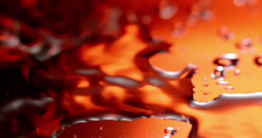 A drop of water creates a ripple effect on an orange surface