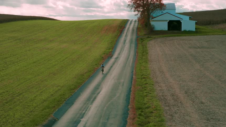 Cyclist riding through the countryside on a lone road