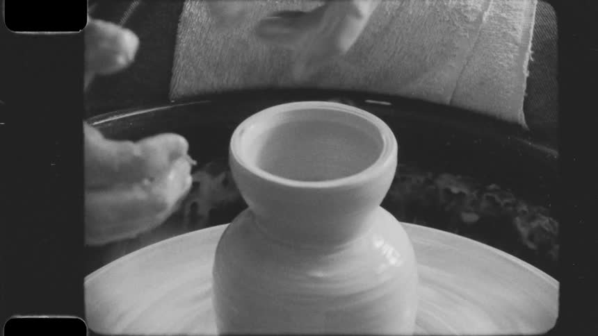 Man uses his fingers to shape the neck of pottery on the pottery wheel