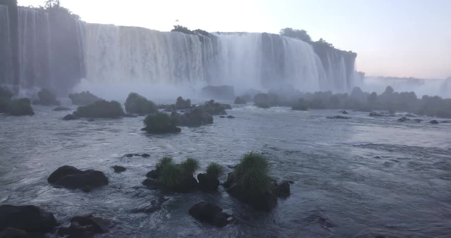 Dense fog rolls in around a powerful waterfall partially obscuring the mist and flowing water