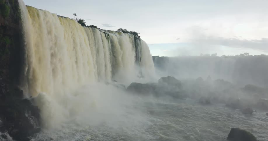 A powerful waterfall cascading over a cliff into a misty rocky basin below