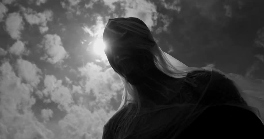 A person is wrapped in plastic with the plastic stretched out behind them set against a cloudy sky