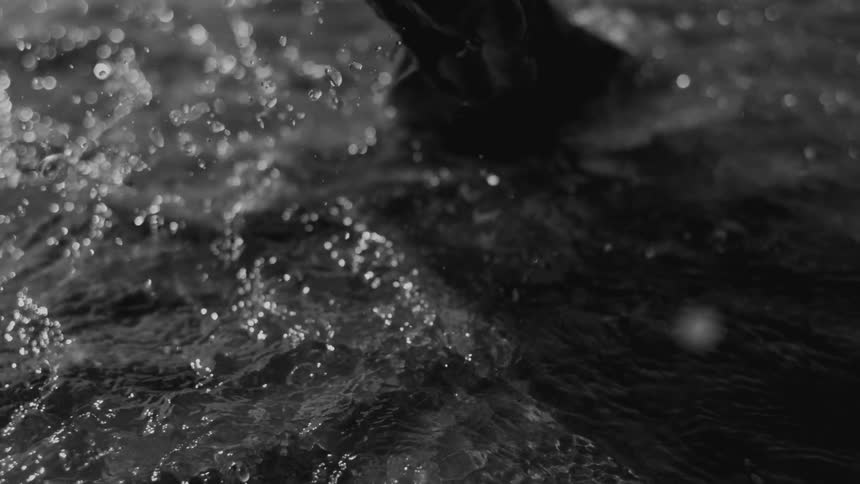 A person runs barefoot through a puddle on wet beach sand