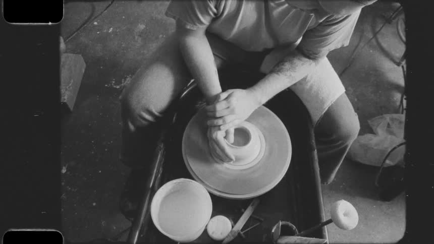 Man shapes a pot while sitting at a pottery wheel