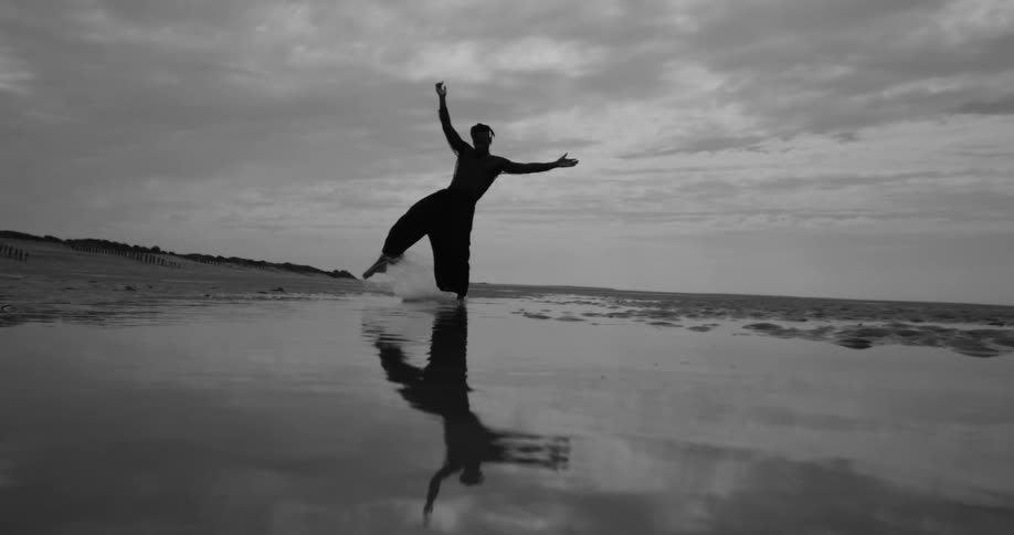 A man kicks his leg high on the beach