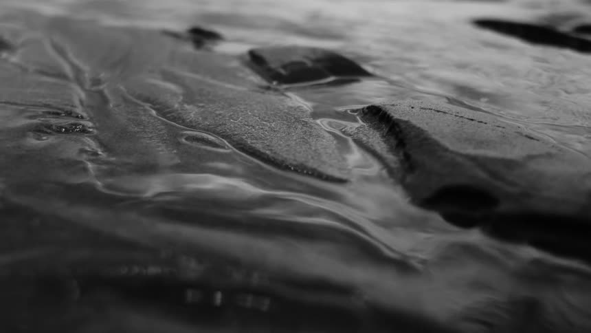 Close up of dark and wet textured sand creating intricate patterns and reflections