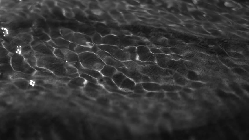 Closeup of small waves and ripples on the waters surface with sunlight creating intricate patterns