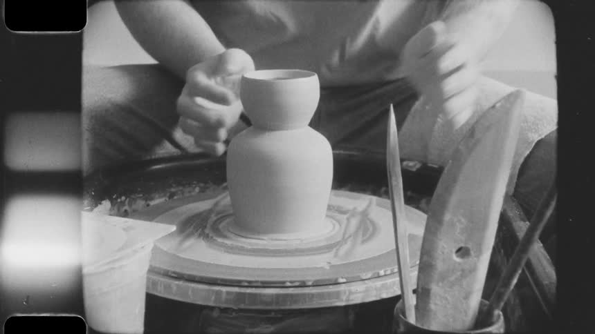 A person centers clay on a pottery wheel and shapes it into a vase