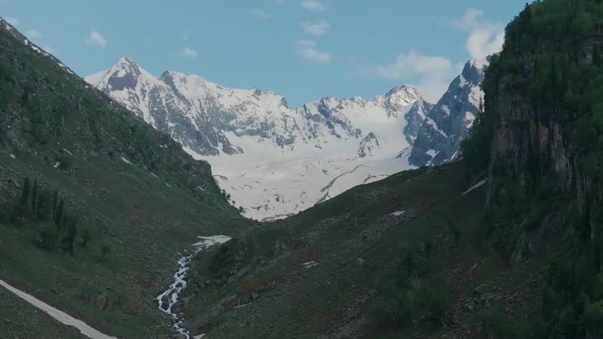 Aerial view of a mountain range with some having snow on them and some having grass