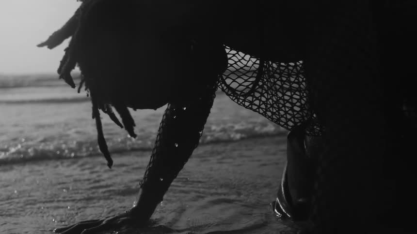 Person kneeling in shallow water at beach