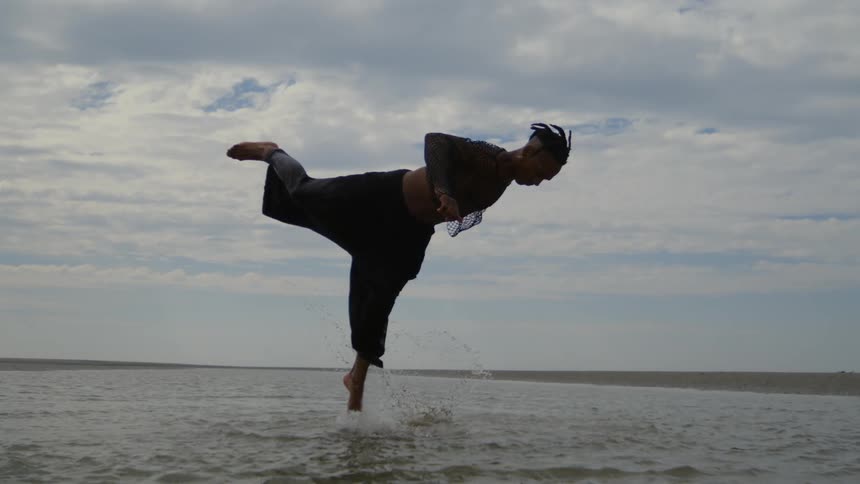 A man jumps high in the air on the beach
