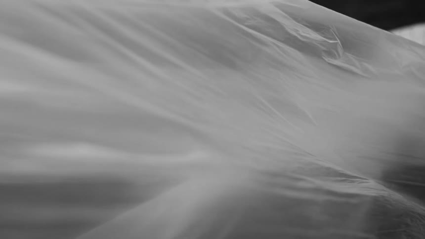 Translucent fabric waves gracefully in the wind against a blurry background creating soft flowing folds