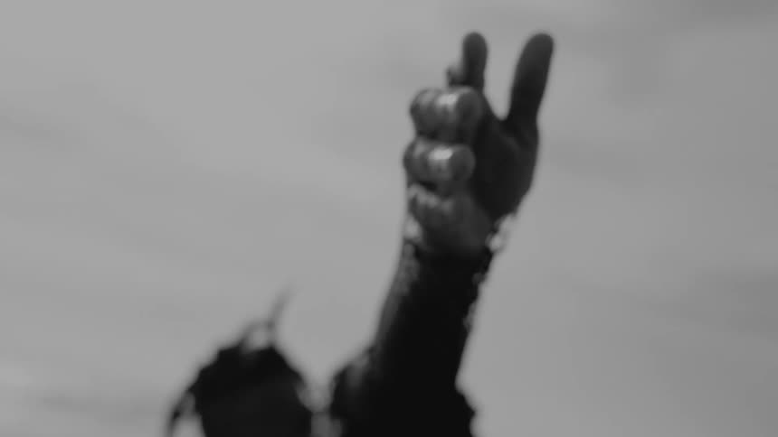 A man swings his arm towards the cloudy sky