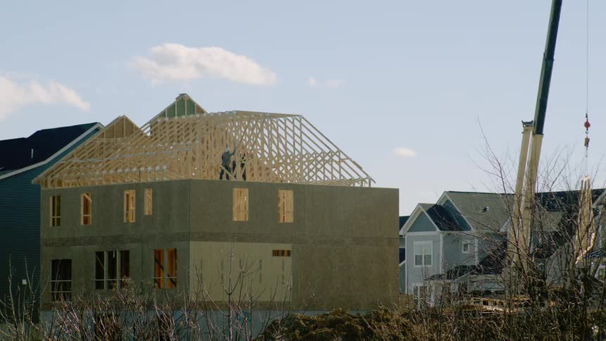 Person working on a house structure on an upper floor under construction