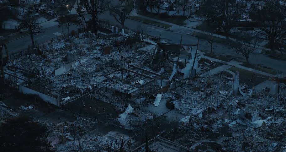 An aerial view of a neighborhood with extensive fire damage where multiple buildings have been reduced to rubble and charred remains