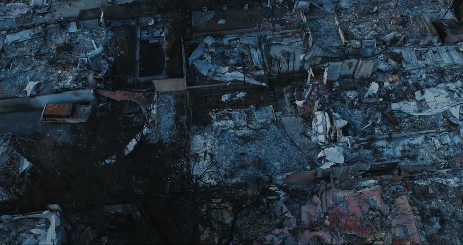 An aerial view of a neighborhood with extensive fire damage where multiple buildings have been reduced to rubble and charred remains