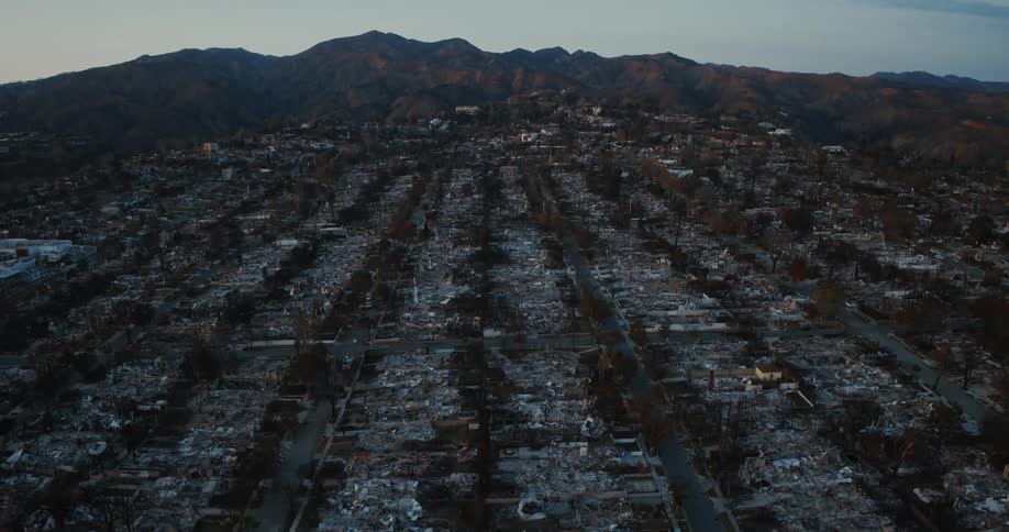 An aerial view of a neighborhood with extensive fire damage where multiple buildings have been reduced to rubble and charred remains