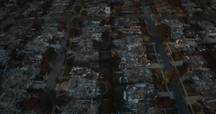 An aerial view of a neighborhood with extensive fire damage where multiple buildings have been reduced to rubble and charred remains